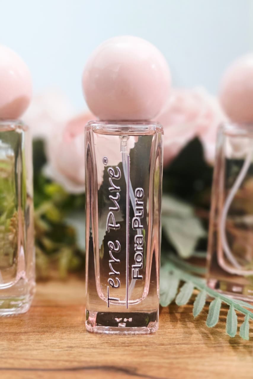 Three small glass bottles labeled 'Terre Pure' and 'Flora Pure' on a wooden surface with a blurred natural background.