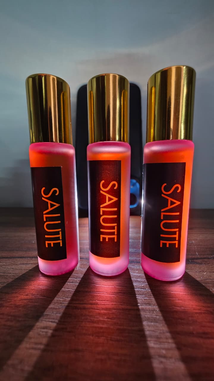 Three 'Salute' Roll on bottles with gold caps on a wooden surface.